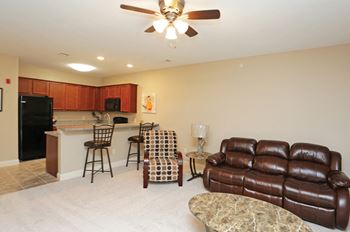 A living room with a brown leather couch and a kitchen area in the background.